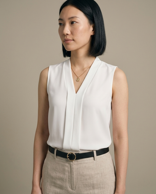 White Sleeveless V-Neck Pleated Blouse worn by a model, close waist-up view
